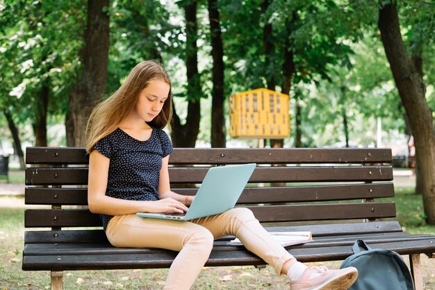 Muchacha que mira la computadora portátil y que estudia