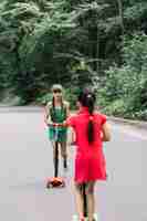 Foto gratuita muchacha que mira a su amigo que monta la vespa en el camino