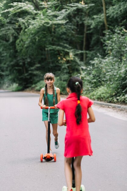 Muchacha que mira a su amigo que monta la vespa en el camino