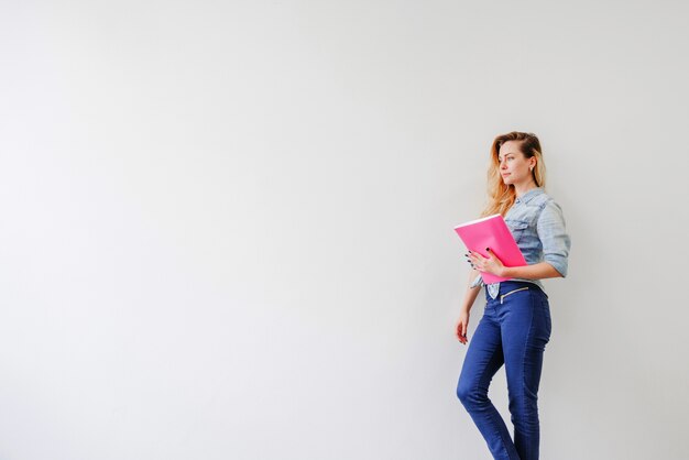 Muchacha que presenta con el cuaderno rosado