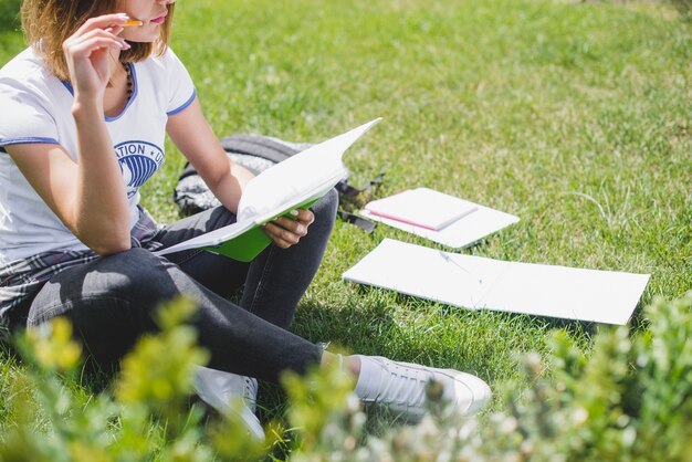 Muchacha que se sienta en la lectura de la hierba