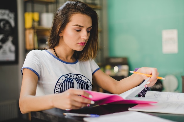 Foto gratuita muchacha que se sienta en la lectura de la tabla