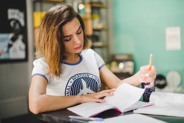 Foto gratuita muchacha que se sienta en la lectura de la tabla