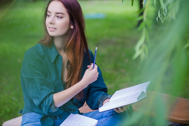 Muchacha que se sienta en libro de explotación del parque