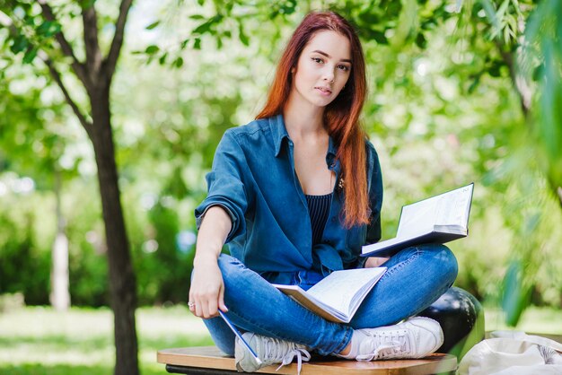 Muchacha que se sienta en el libro de explotación de la tabla