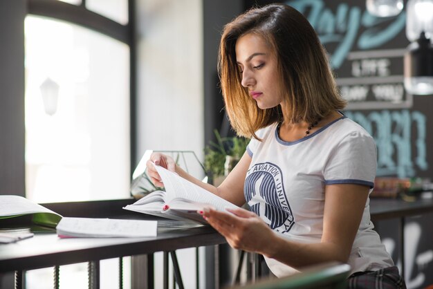 Muchacha que se sienta en el libro de lectura de la tabla