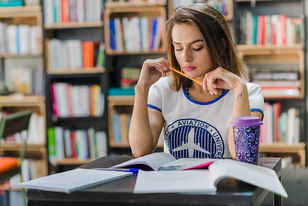 Muchacha que se sienta en la tabla con los cuadernos