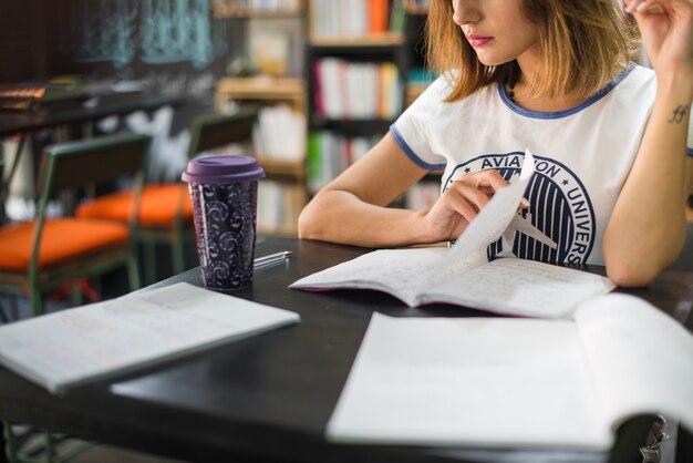 Muchacha que se sienta en la tabla con los cuadernos