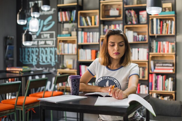 Muchacha que se sienta en la tabla con los cuadernos