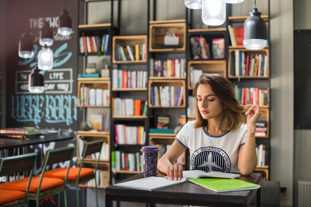 Foto gratuita muchacha que se sienta en la tabla con los cuadernos