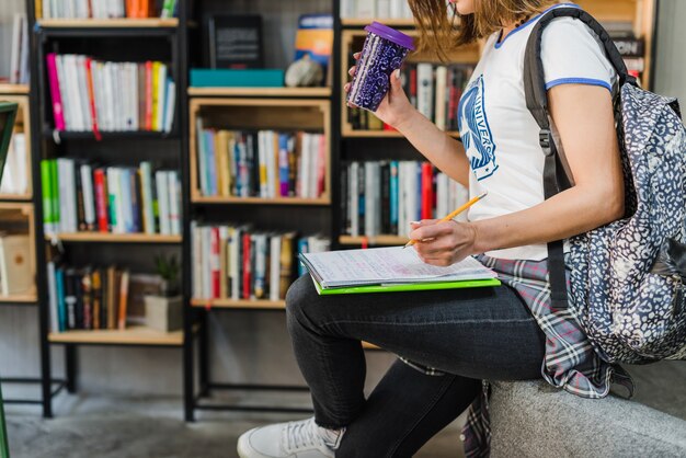 Muchacha que sostiene el cuaderno en la escritura de la rodilla