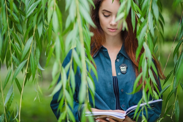 Muchacha que sostiene los cuadernos que leen en parque