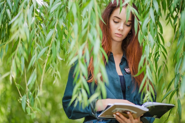 Muchacha que sostiene los cuadernos que leen en parque