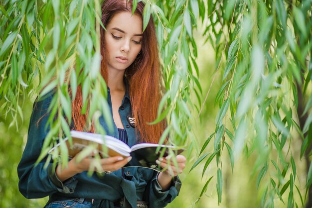 Muchacha que sostiene los cuadernos que leen en parque