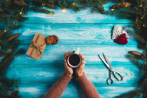 Muchacha que sostiene una taza de cacao caliente en un fondo azul de madera. Concepto de Navidad.