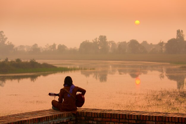 Muchacha que toca la guitarra al atardecer