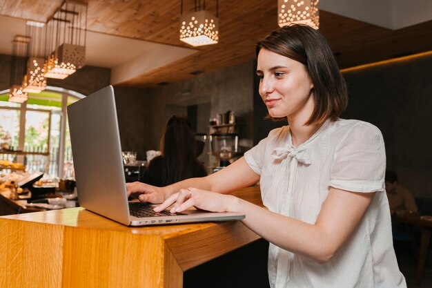 Muchacha que trabaja en la computadora portátil en el café