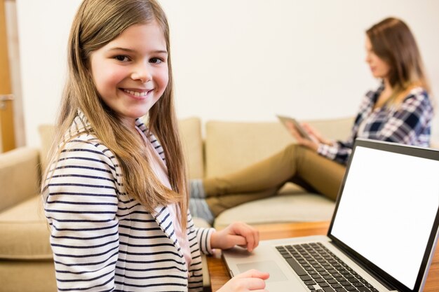 Muchacha que usa el ordenador portátil en la sala de estar