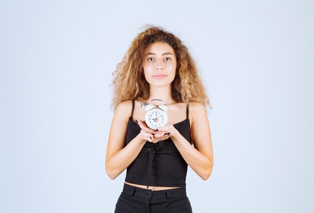 Foto gratuita muchacha rubia que sostiene un reloj de alarma.