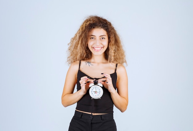 Foto gratuita muchacha rubia que sostiene un reloj de alarma.