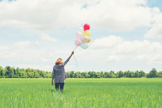 Muchacha solitaria con globos multicolores