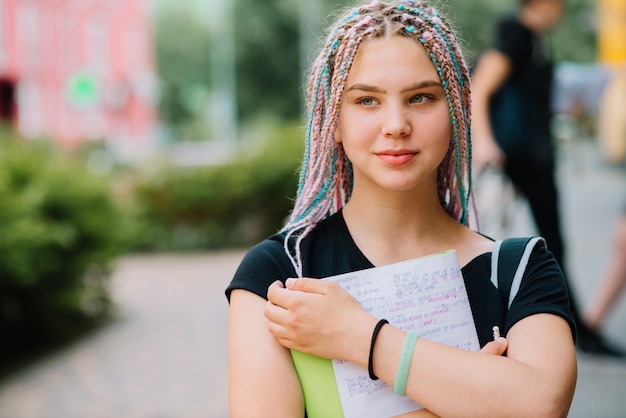 Muchacha soñadora que abraza el libro de texto