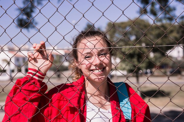 Muchacha sonriente joven que se coloca detrás de rejilla