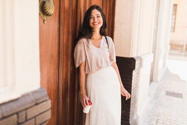 Muchacha sonriente que sostiene la taza de café disponible