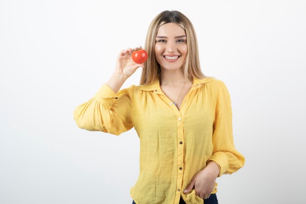 Muchacha sonriente que sostiene el tomate rojo en blanco.