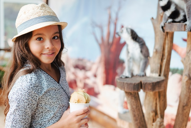 Foto gratuita muchacha sonriente que sostiene el vidrio de rebanadas de la manzana en el parque zoológico