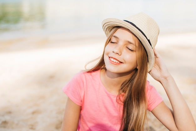 Muchacha sonriente en sombrero que disfruta de la sol