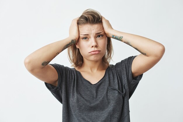 Muchacha trastornada nerviosa hermosa joven que piensa sosteniendo la cabeza.