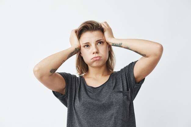 Muchacha trastornada nerviosa hermosa joven que piensa sosteniendo la cabeza.