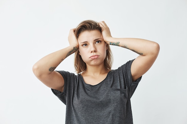 Muchacha trastornada nerviosa hermosa joven que piensa sosteniendo la cabeza.