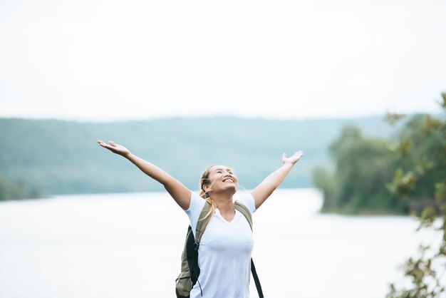 Muchacha turística con los brazos felices con la naturaleza cerca del río. Concepto de viaje