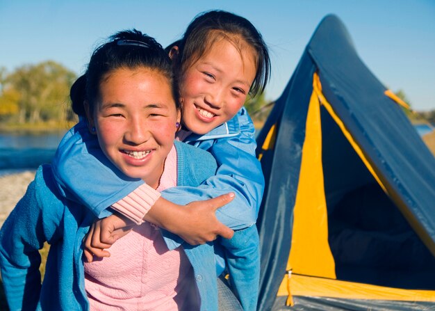 Muchachas felices de Mongolia que juegan a cuestas en el sitio para acampar.