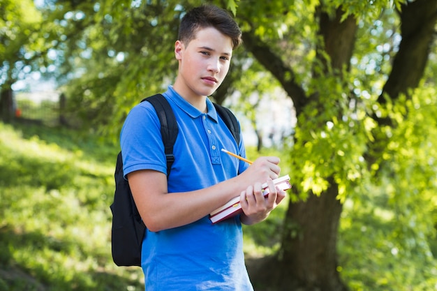 Muchacho adolescente de la escritura que mira la cámara atentamente