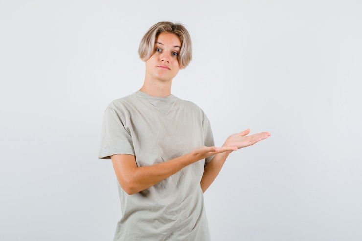Foto gratuito muchacho adolescente joven que muestra gesto de bienvenida en camiseta y que parece suave. vista frontal.