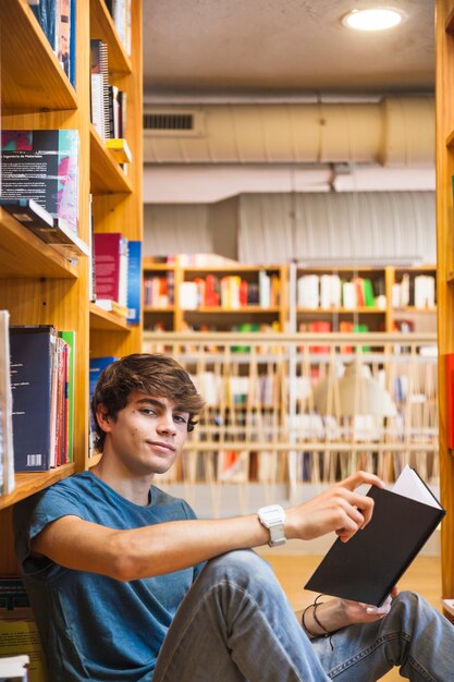 Muchacho adolescente con el libro que mira la cámara