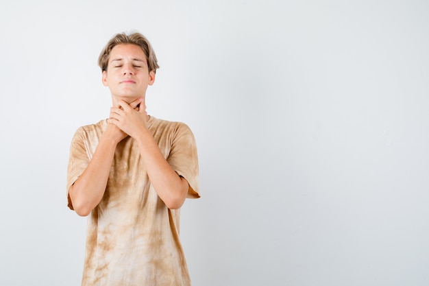 Muchacho adolescente que sufre de dolor de garganta en camiseta y parece enfermo. vista frontal.