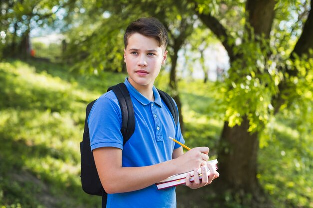 Muchacho adolescente serio que camina y que escribe