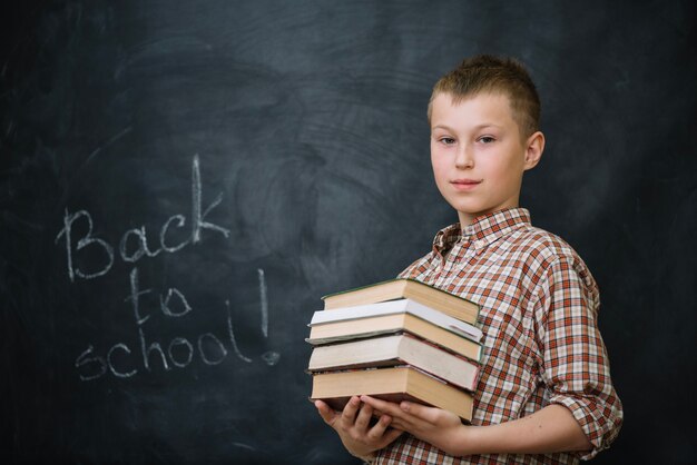 Muchacho en la camisa a cuadros que sostiene los libros