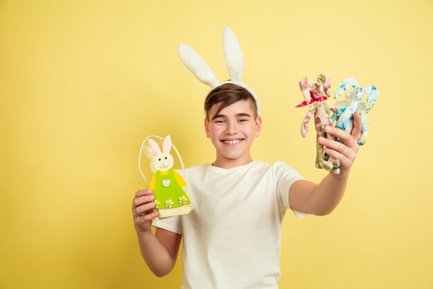 Muchacho caucásico como un conejito de Pascua en el fondo amarillo del estudio.