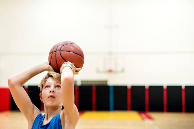 Muchacho caucásico joven que juega al baloncesto del tiroteo en estadio