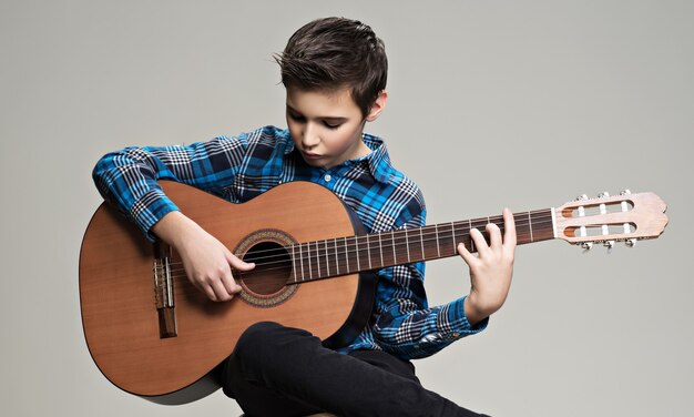 Muchacho caucásico tocando la guitarra acústica.