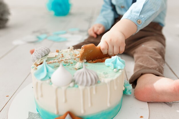 Muchacho de cumpleaños caucásico piernas y brazos mientras destruye y rompe su pastel de crema