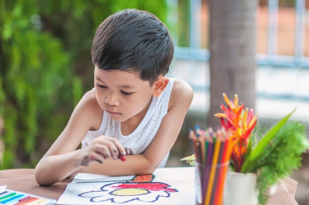 El muchacho está pintando el cuadro colorido en casa.