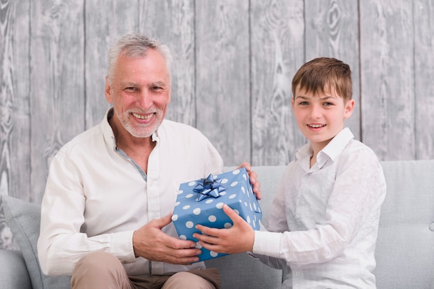 Muchacho feliz que da el regalo de cumpleaños a su abuelo