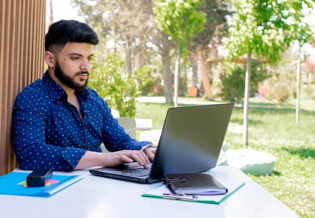 Muchacho moreno con barba trabajando en la computadora portátil escribiendo