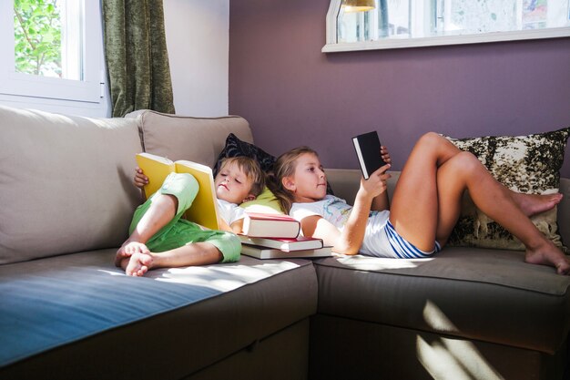 Muchacho y muchacha con los libros en sofá